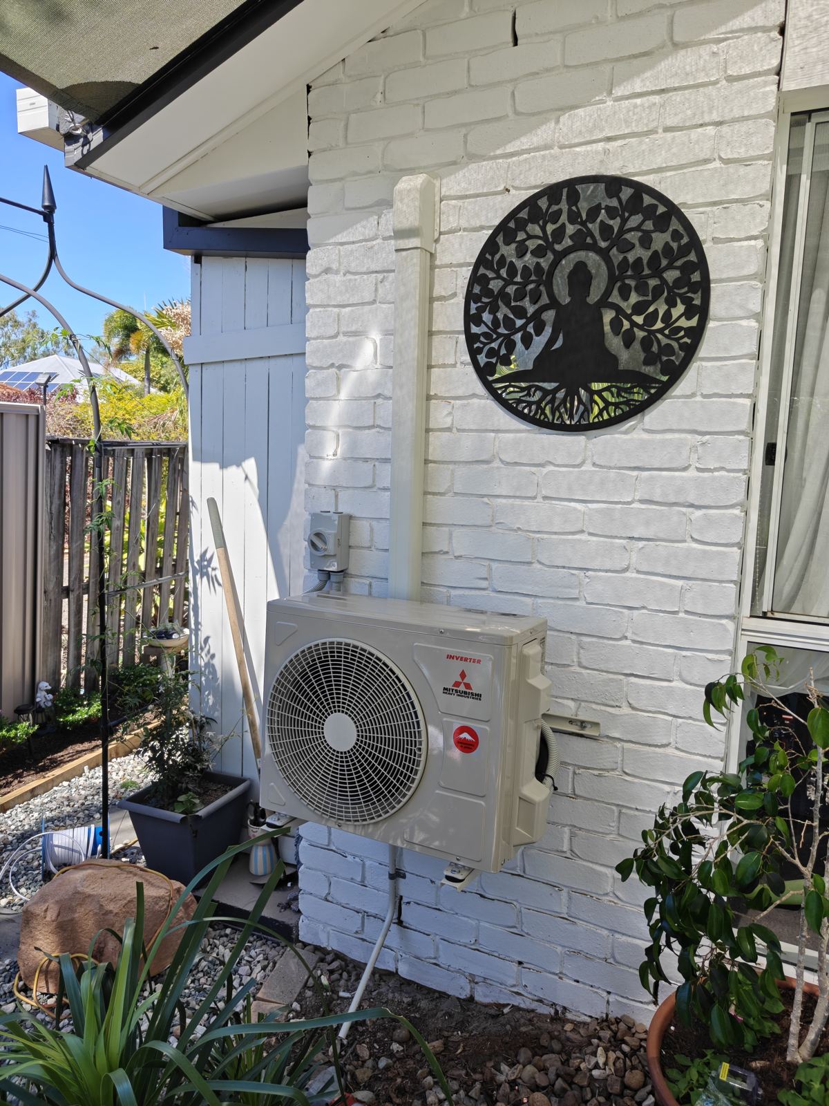 Mitsubishi split system outdoor unit on a white brick wall